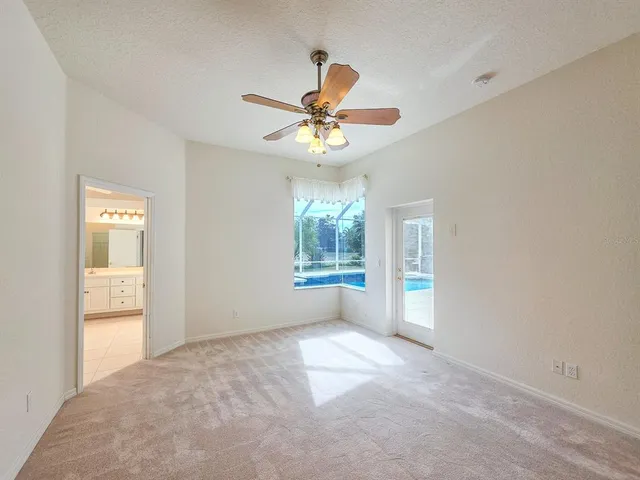 a view of an empty room with a window and chandelier fan