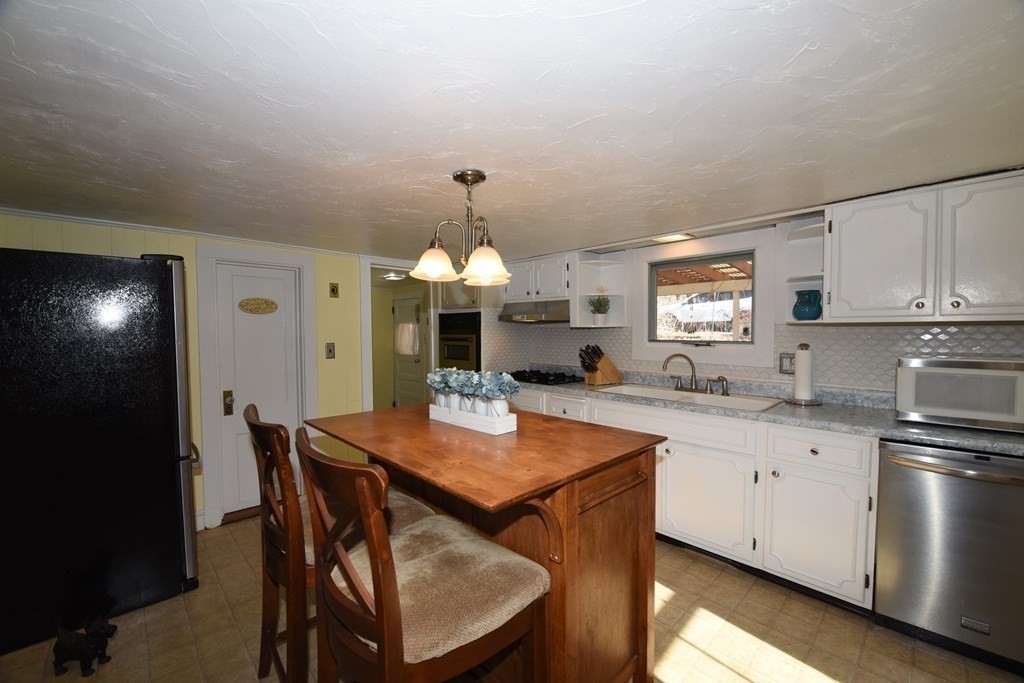 7 Summer Street Kingston, MA 02364 - Photo 13 of 41 a kitchen with stainless steel appliances kitchen island granite countertop a table chairs sink and cabinets