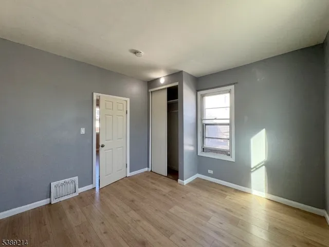 a view of an empty room with window and wooden floor
