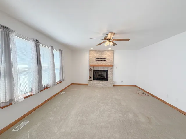 an empty room with windows and fireplace