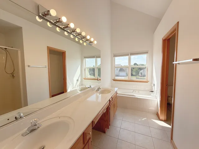 a spacious bathroom with a tub sink and a mirror