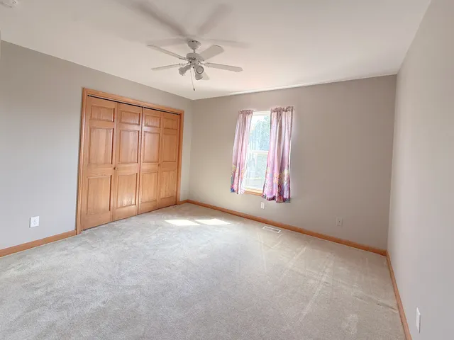 an empty room with windows and chandelier fan