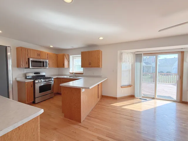 a large kitchen with stainless steel appliances granite countertop a stove a sink dishwasher a refrigerator and a oven with wooden floor