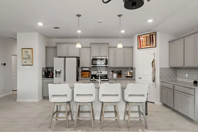 a kitchen with stainless steel appliances kitchen island granite countertop a refrigerator and microwave