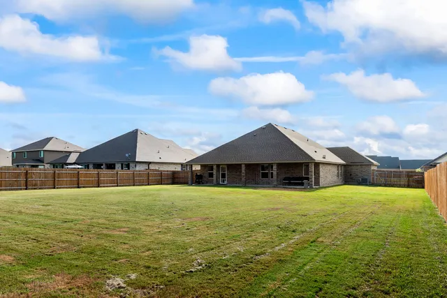 a view of a house with a big yard and large trees