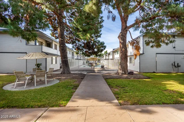 a view of a patio with table and chairs and potted plants and large trees