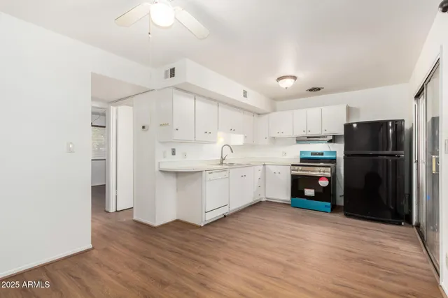 a kitchen with stainless steel appliances a refrigerator a sink and white cabinets