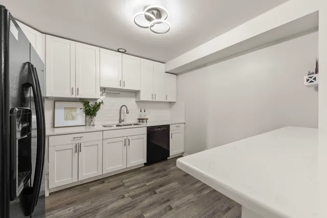 a kitchen with a sink a refrigerator and white cabinets