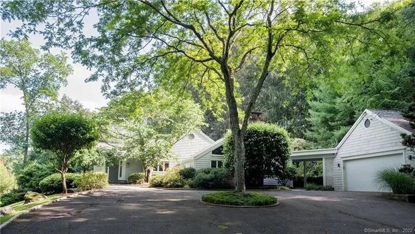 a view of a house with a yard and large trees