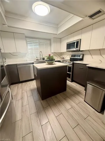 a kitchen with stainless steel appliances kitchen island granite countertop a refrigerator and a stove top oven