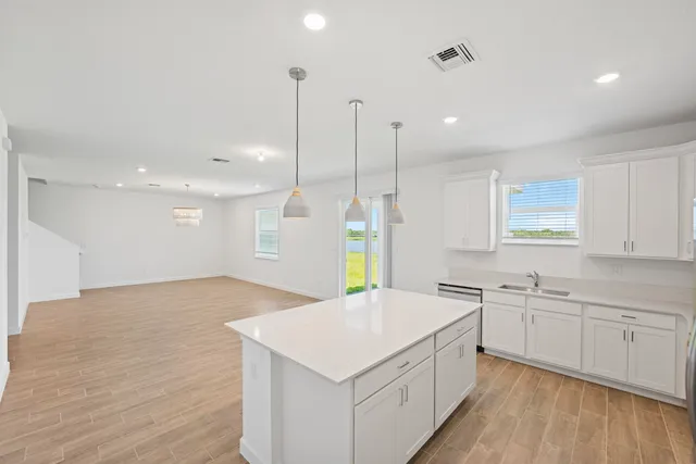 a kitchen with a sink dishwasher and white cabinets with wooden floor