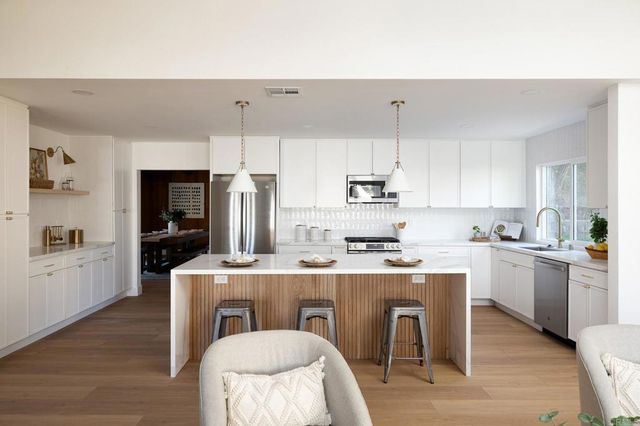 a kitchen with stainless steel appliances kitchen island granite countertop a table chairs microwave and sink