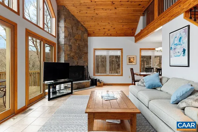 a living room with furniture a flat screen tv and a floor to ceiling window