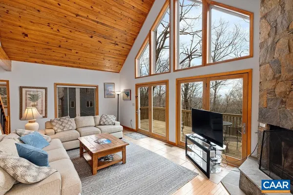 a living room with furniture a flat screen tv and a floor to ceiling window