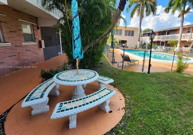 a front view of a house with swimming pool table and chairs