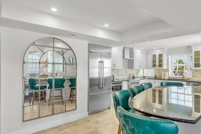 a kitchen with stainless steel appliances granite countertop a stove a refrigerator a couch and a dining table with garden view