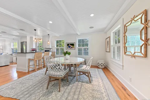 a dining room with wooden floor and large windows