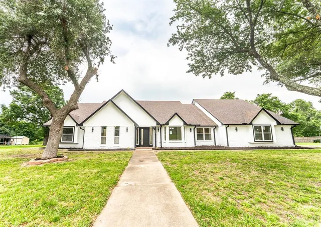 a view of a house with a big yard and large trees