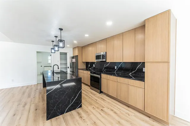 a kitchen with stainless steel appliances kitchen island granite countertop a stove a sink a refrigerator and cabinets