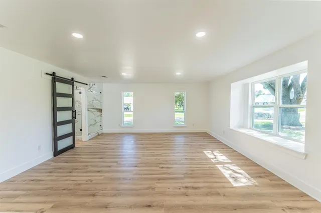 a view of an empty room with a window and wooden floor