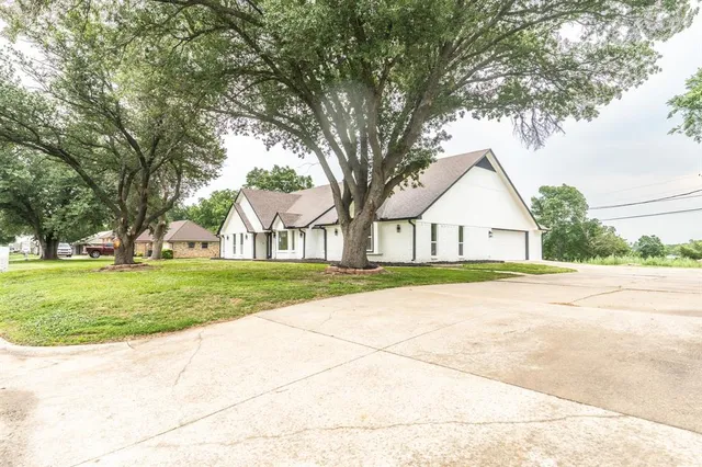 a view of large trees in front of a house