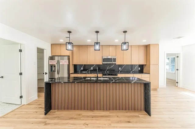 a kitchen with stainless steel appliances granite countertop a sink stove and refrigerator