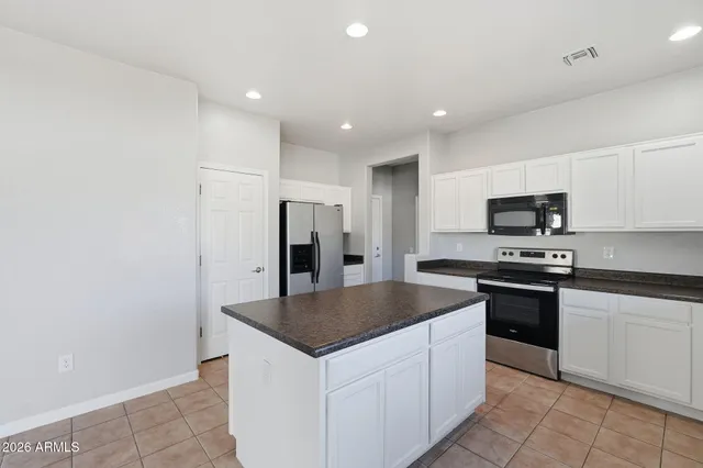 an empty room with chandelier fan and windows