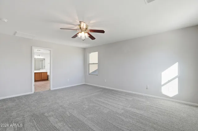 a view of an empty room with chandelier fan and a window