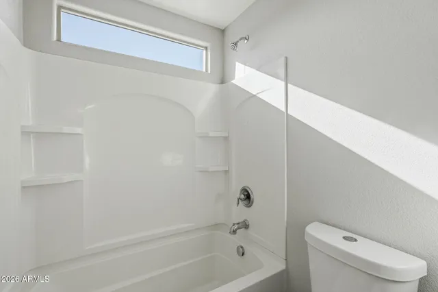 a view of an empty room with a ceiling fan and window