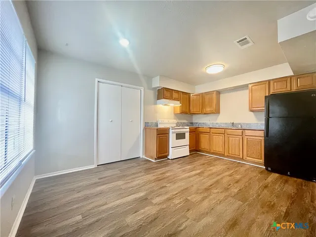 a kitchen with a refrigerator and white cabinets