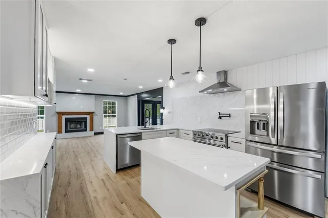 an empty room with wooden floor fireplace and windows