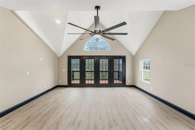 an empty room with wooden floor closet and windows