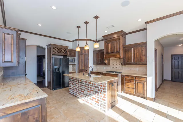 a kitchen with kitchen island granite countertop wooden cabinets and a refrigerator