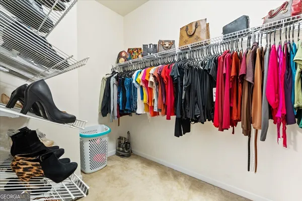 a view of walk in closet with clothes and shoes