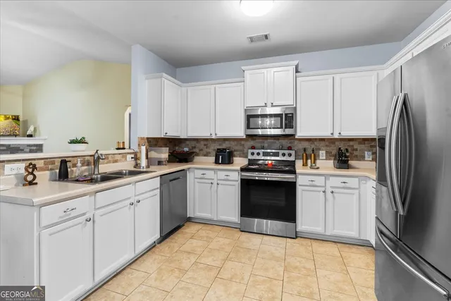 a kitchen with granite countertop a sink a counter top space stainless steel appliances and cabinets
