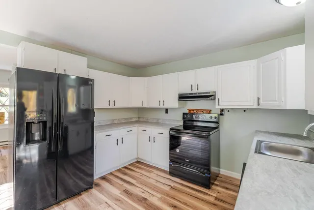 a kitchen with granite countertop a refrigerator stove and white cabinets