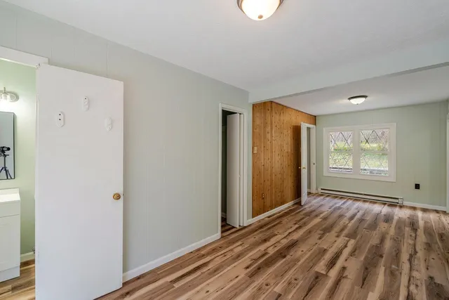 a view of an empty room with wooden floor and a window