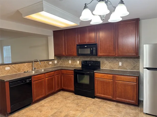 a kitchen with stainless steel appliances granite countertop wooden cabinets a stove a sink and dishwasher