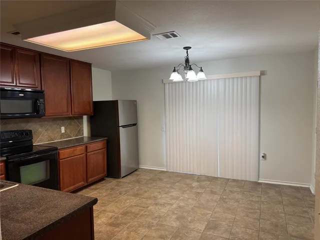 a kitchen with stainless steel appliances granite countertop a refrigerator a sink dishwasher a stove and cabinets with wooden floor