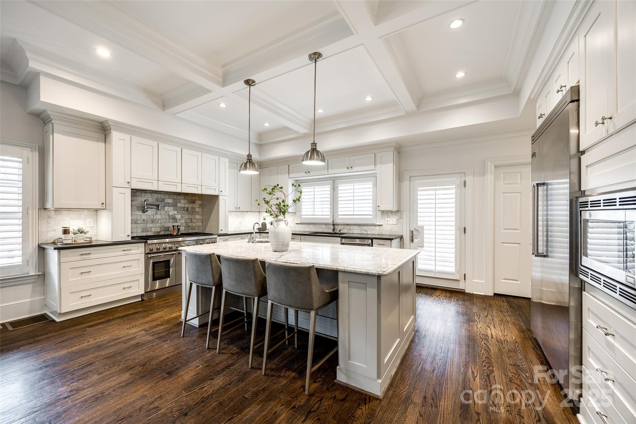 1225 Providence Road Charlotte, NC 28207 - Photo 13 of 42 a kitchen with stainless steel appliances kitchen island granite countertop a wooden floor and white cabinets