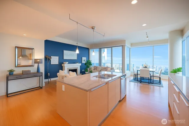 a large living room with stainless steel appliances granite countertop a sink dishwasher a stove and a dining table with wooden floor