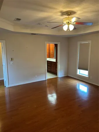 a view of an empty room with wooden floor and a window