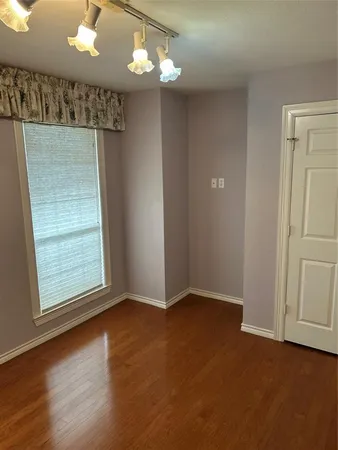 en empty room with window and wooden floor