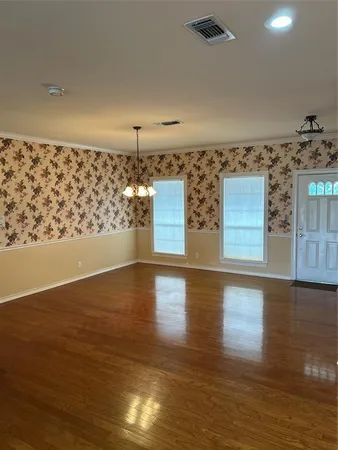 an empty room with wooden floor fireplace and windows