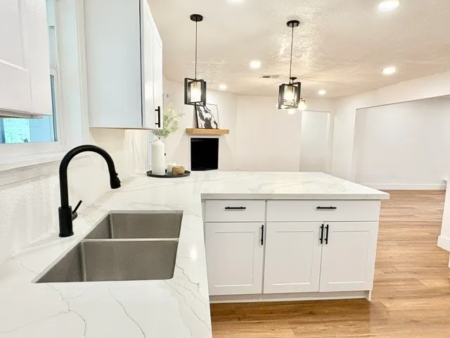 a kitchen with a sink a stove and white cabinets with wooden floor
