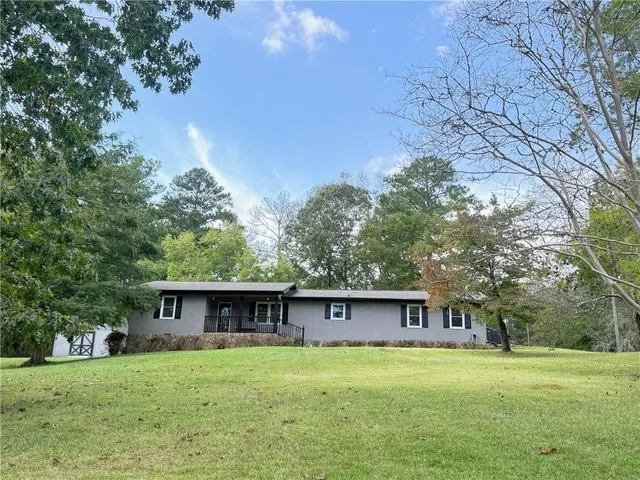 a view of a big house with a big yard and large trees