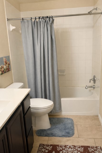 11613 Reading Court Austin, TX 78717 - Photo 13 of 20 Bathroom featuring a white bathtub, ceramic tile shower surround, and a dark wood-finish vanity with a white countertop