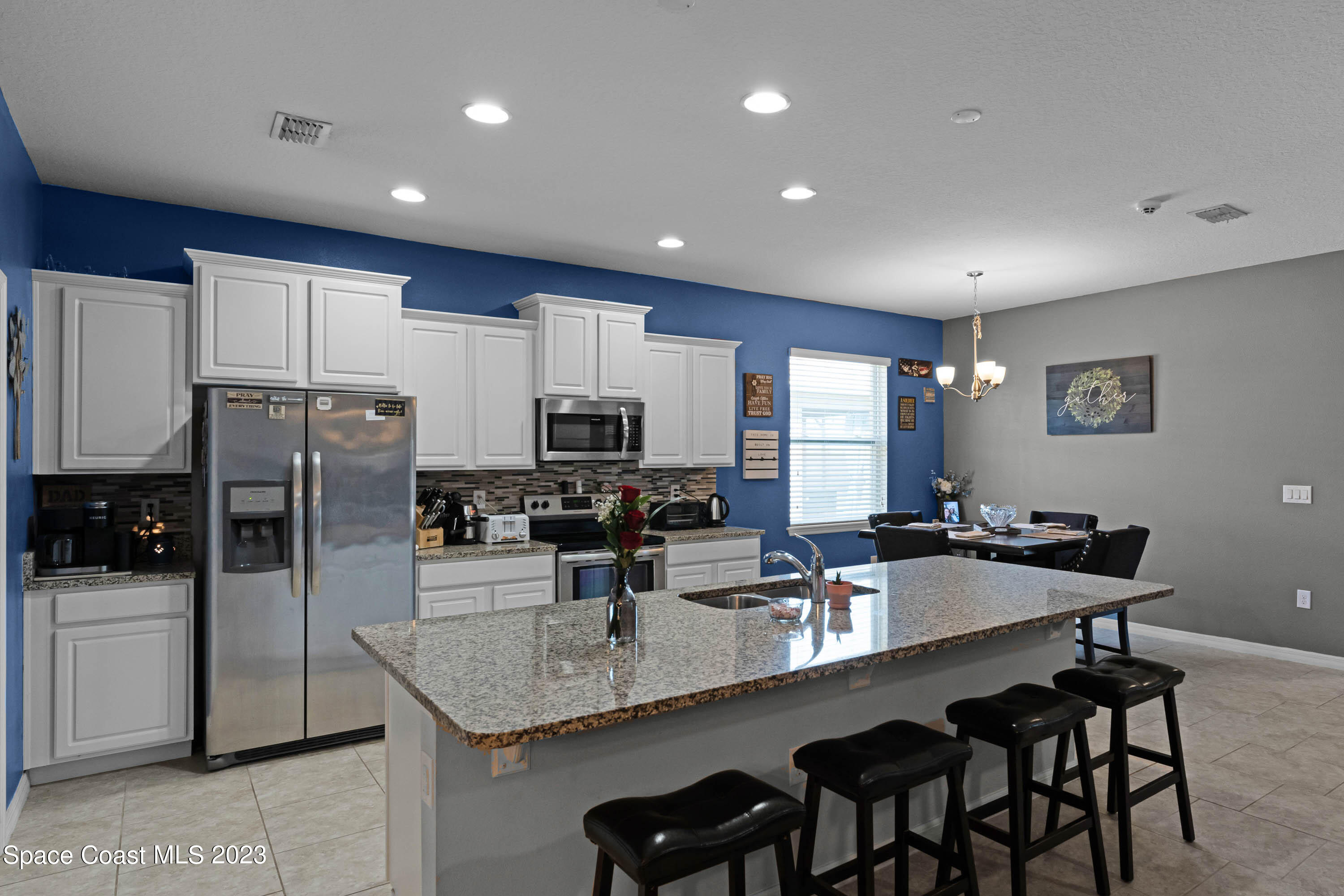 1803 Brockridge Road Kissimmee, FL 34744 - Photo 14 of 46 a kitchen with stainless steel appliances granite countertop a dining table chairs refrigerator and microwave