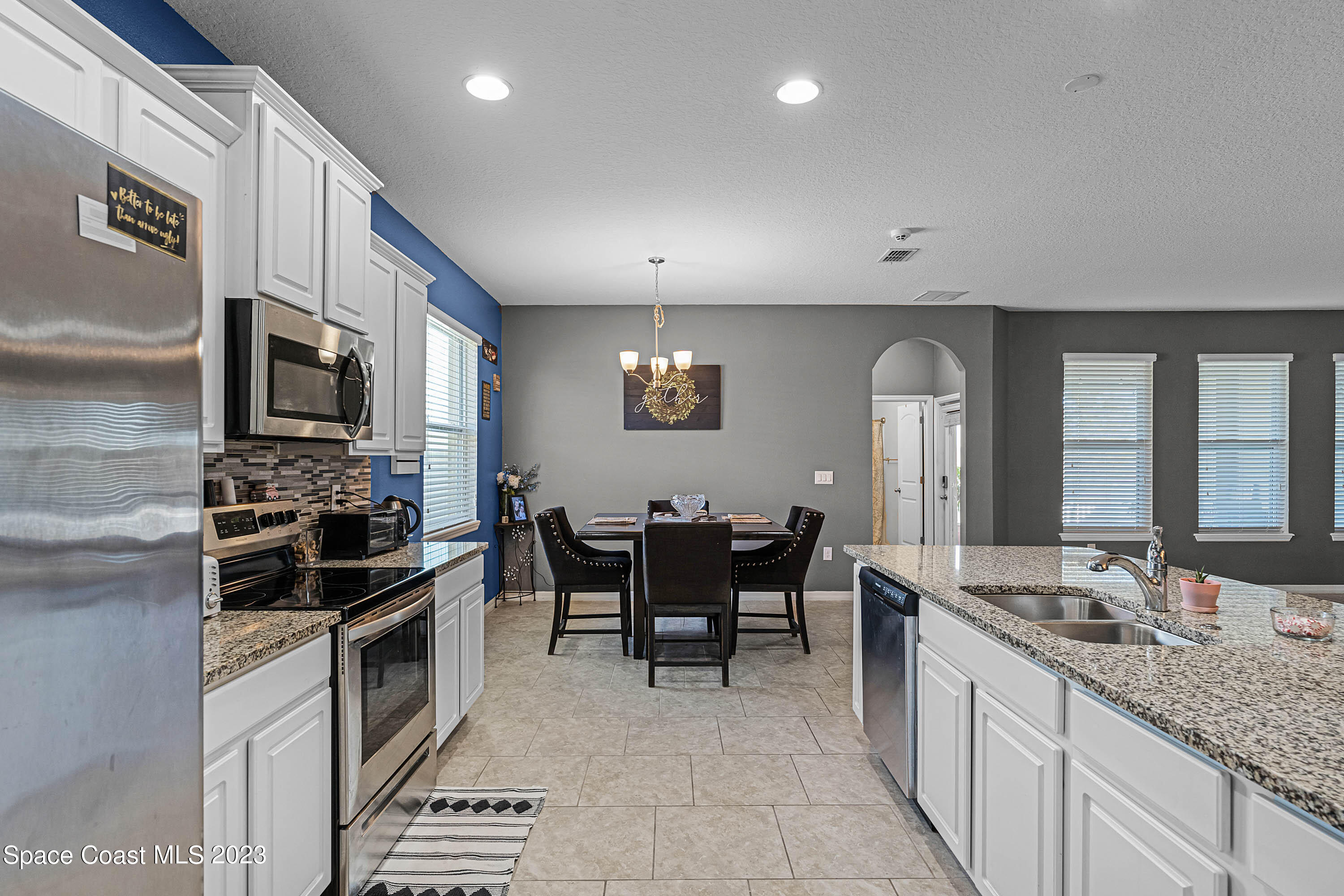 1803 Brockridge Road Kissimmee, FL 34744 - Photo 33 of 46 a large kitchen with stainless steel appliances granite countertop a stove top oven a sink dishwasher a dining table and chairs with wooden floor