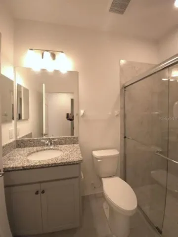 a bathroom with a granite countertop sink a toilet and shower